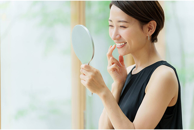 鏡に映る自分の歯を見て微笑む女性